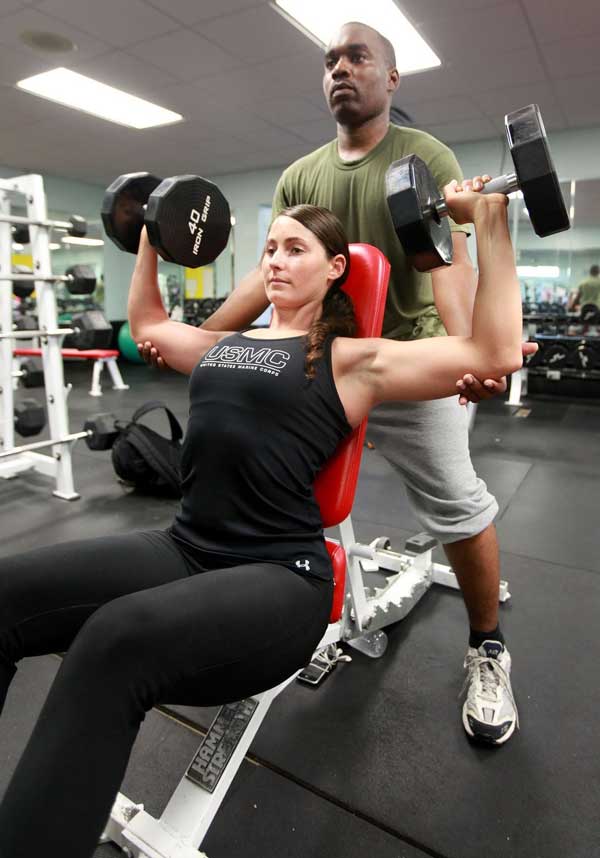 Una mujer haciendo ejercicio en el gimnasio y el instructor guiándola