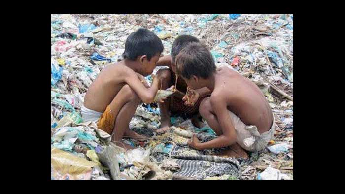 3 kids  in  rubbish dump eating   something  they   apparently  found  in the  garbage