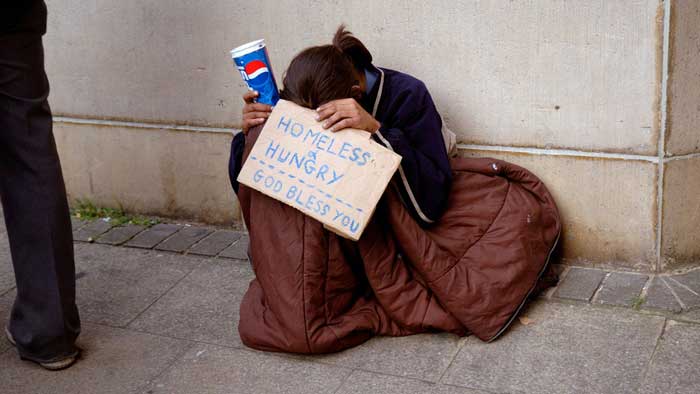 Girl sitting  on street  begging while holding  sign that  reads: ‘Homeless & hungry God bless  you’