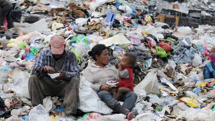 Couple  and  baby sitting  on rubbish  dump  while  eating  food