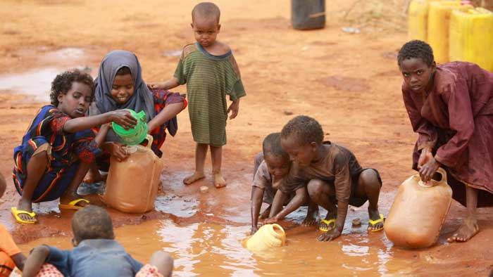 8 niños recogiendo agua de un pozo pantanoso