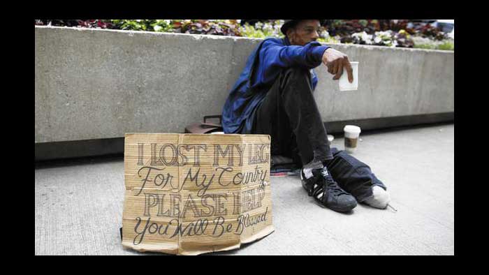 Young  man one leg missing, begging  on street with  a  sign  by his  side  that reads: ‘Lost my  leg  for  my  country.   Please   help,  you  will   be  blessed’