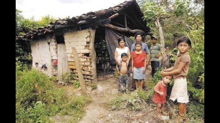 Familia compuesta por 7 personas paradas frente a su choza