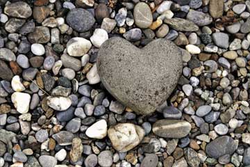 Una piedra con forma de corazón rodeada de muchas piedras pequeñas